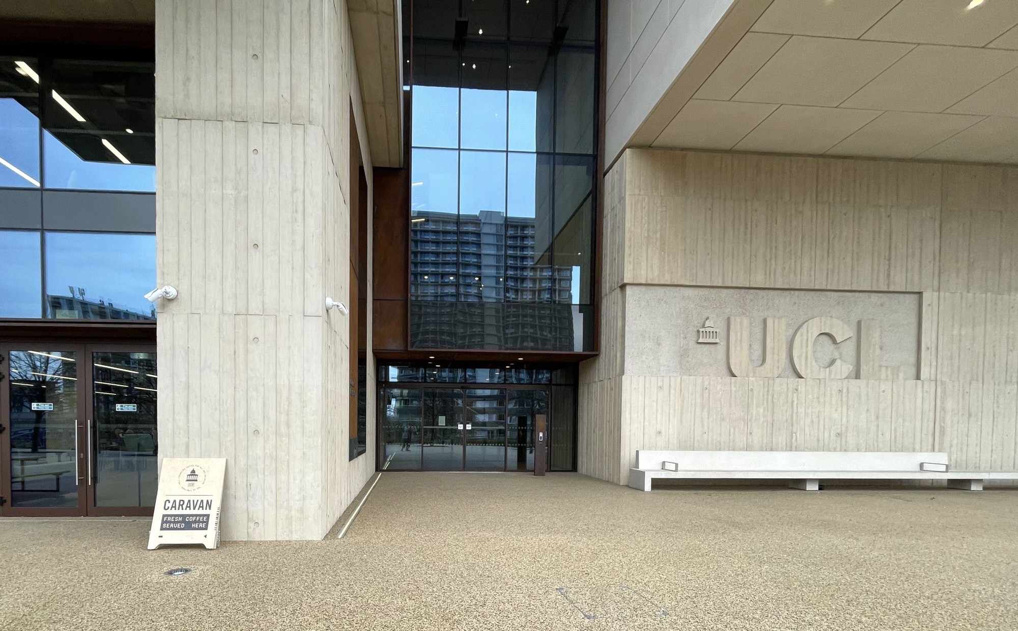 A building with a glass entrance wall and the UCL logo